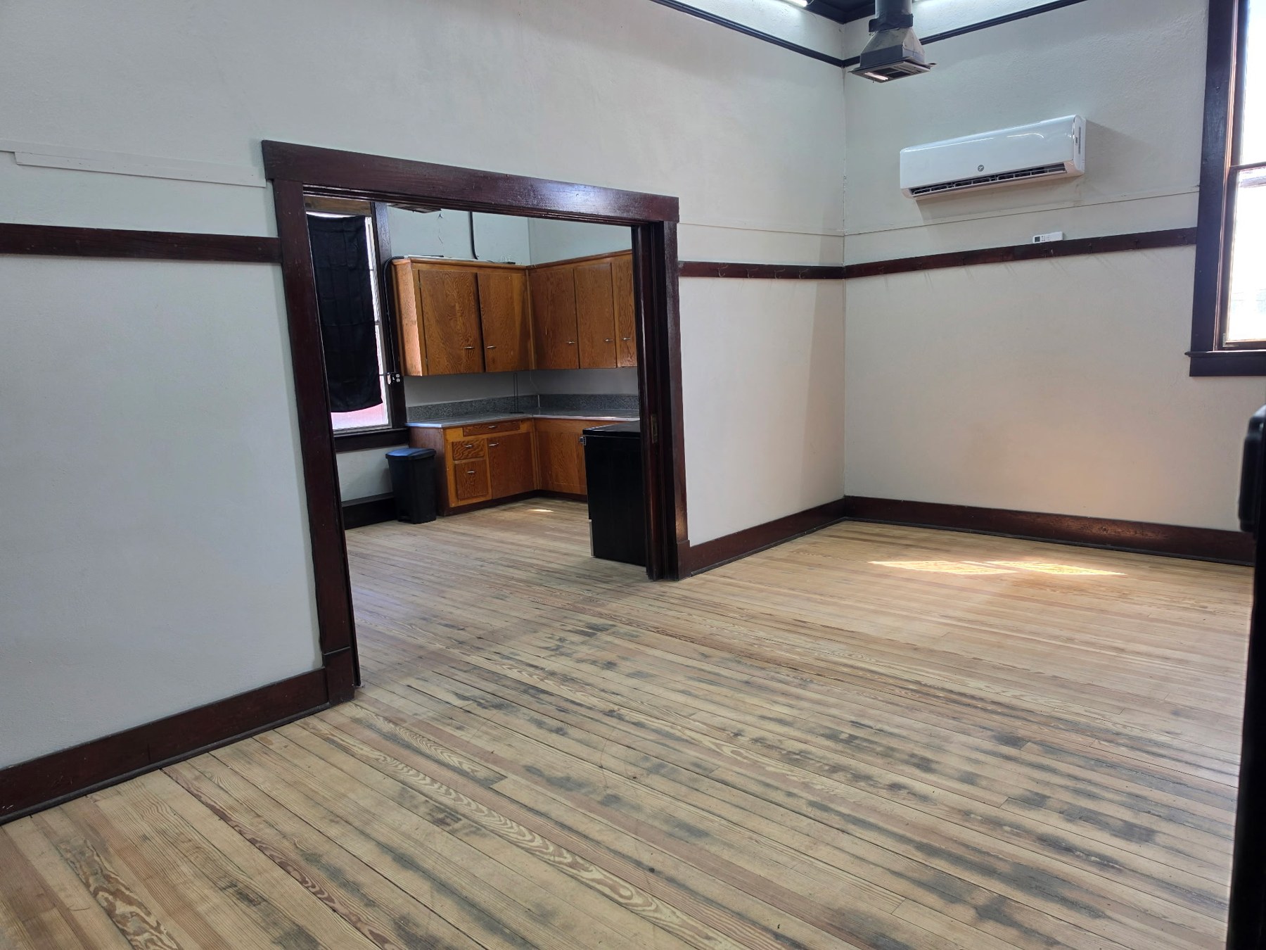 Apartment living area opening into the kitchen, with wood floors and dark wood trim