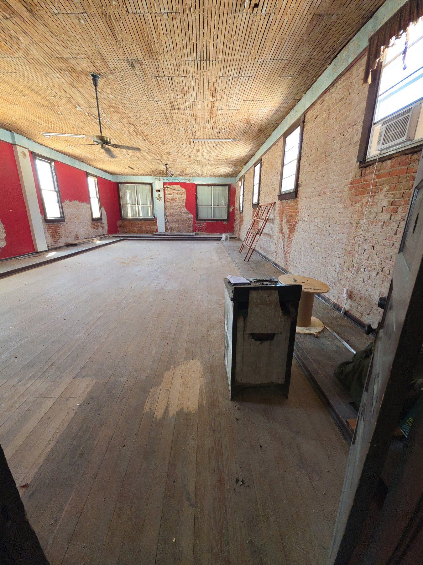Large upstairs ballroom with exposed brick, wood floor and exposed ceiling lath during renovation
