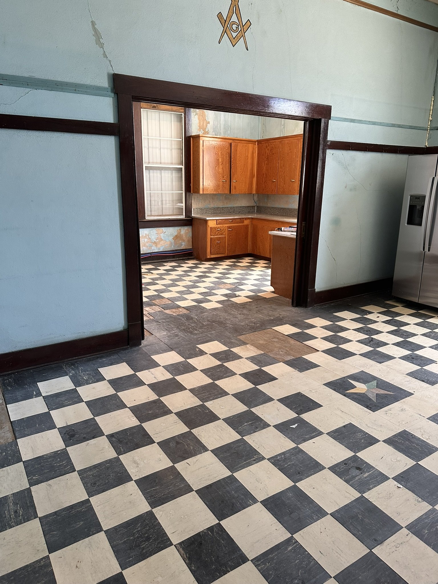 Upstairs kitchen area with cabinetry, dark wood trim and checkerboard flooring during renovation